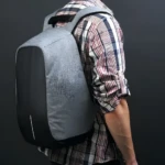 Mochila morral antirobo gris y negra para hombre, con diseño moderno.