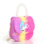 Bolso para niña estilo pop it, color lila, amarillo y fucsia, con unicornio y cadena dorada.