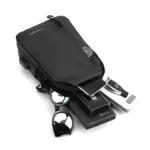 Bolso pechero negro con accesorios: celular, llaves, cartera, gafas de sol y reloj.