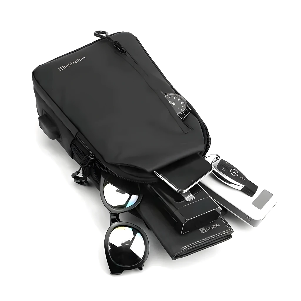 Bolso pechero negro con accesorios: celular, llaves, cartera, gafas de sol y reloj.