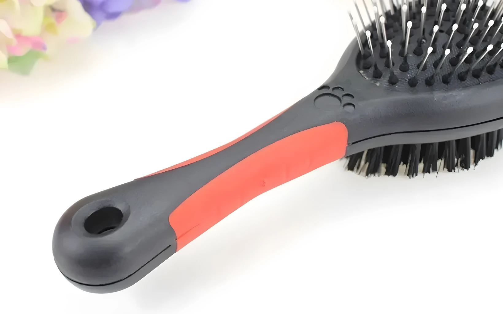 Cepillo para mascotas doble cara con mango ergonómico y hueco para colgar.