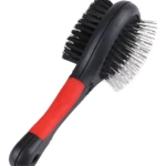 Cepillo doble cara para mascotas con cerdas negras y pines metálicos, mango ergonómico rojo y negro.