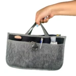 Organizador de bolso gris para dama con compartimentos y logo Nissan.