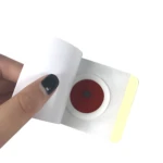 Parches adelgazantes X30 sticker con centro rojo, sostenidos por mano con uñas oscuras.