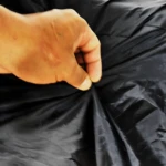 Mano arrugada en pijama para moto forrado, semi impermeable negro y bandera de Colombia.