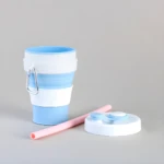Taza de silicona plegable azul y blanca con tapa y pitillo rosa.