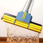 Trapeador de esponja absorbente amarillo y azul sumergiéndose en agua, salpicando líquido.