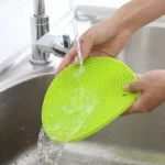 Set x2 soportes de silicona verdes con patrón de panal lavados bajo el grifo.