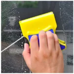 Limpia vidrios magnético amarillo y azul limpiando una ventana con espuma.