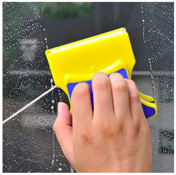 Limpia vidrios magnético amarillo y azul limpiando una ventana con espuma.