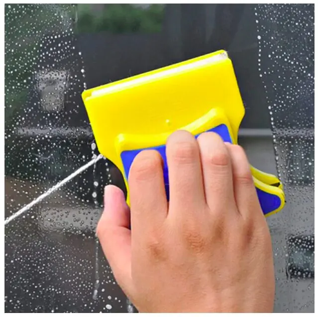 Limpia vidrios magnético amarillo y azul limpiando una ventana con espuma.