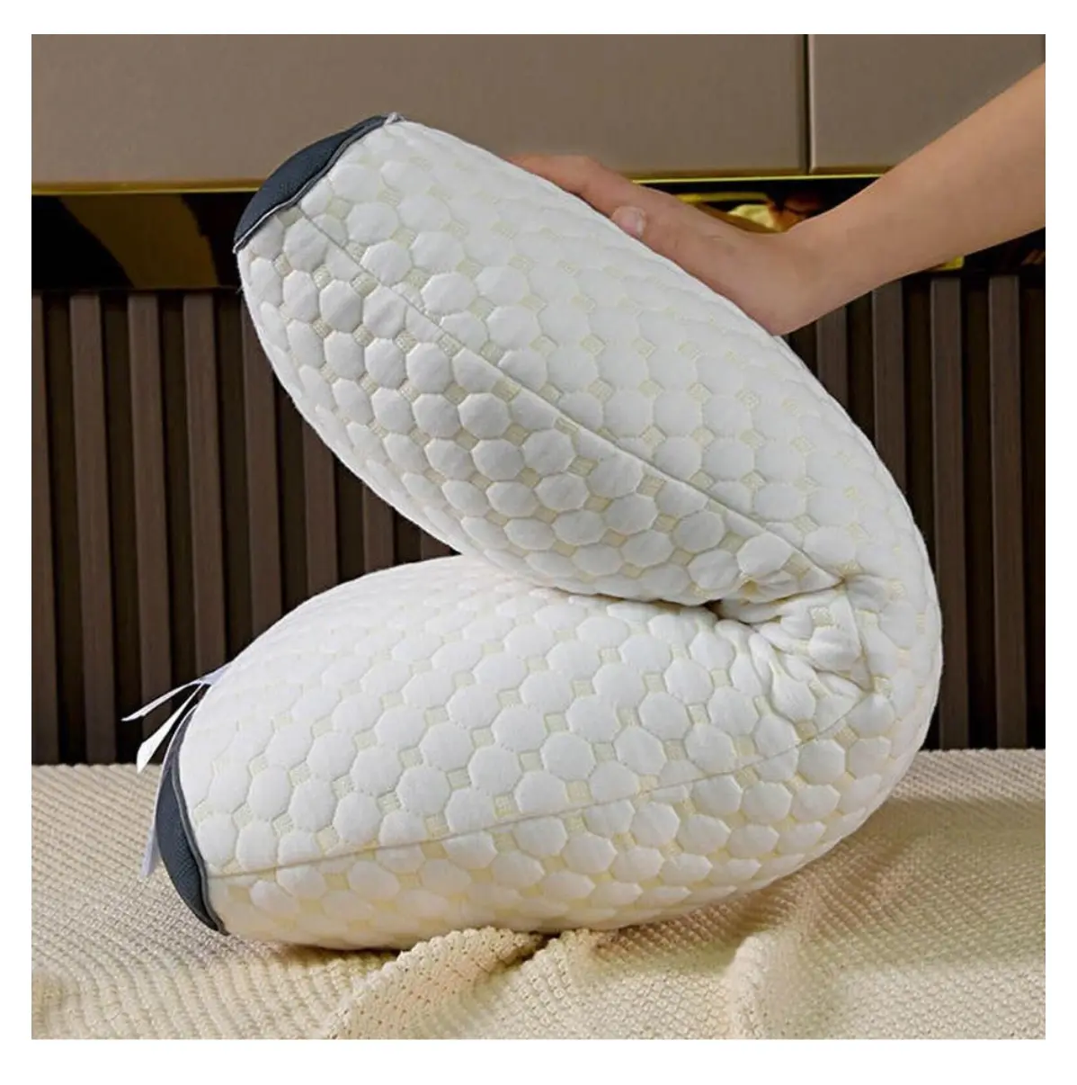 Almohada cervical 3D Desconso blanca con textura hexagonal, sostenida por una mano.