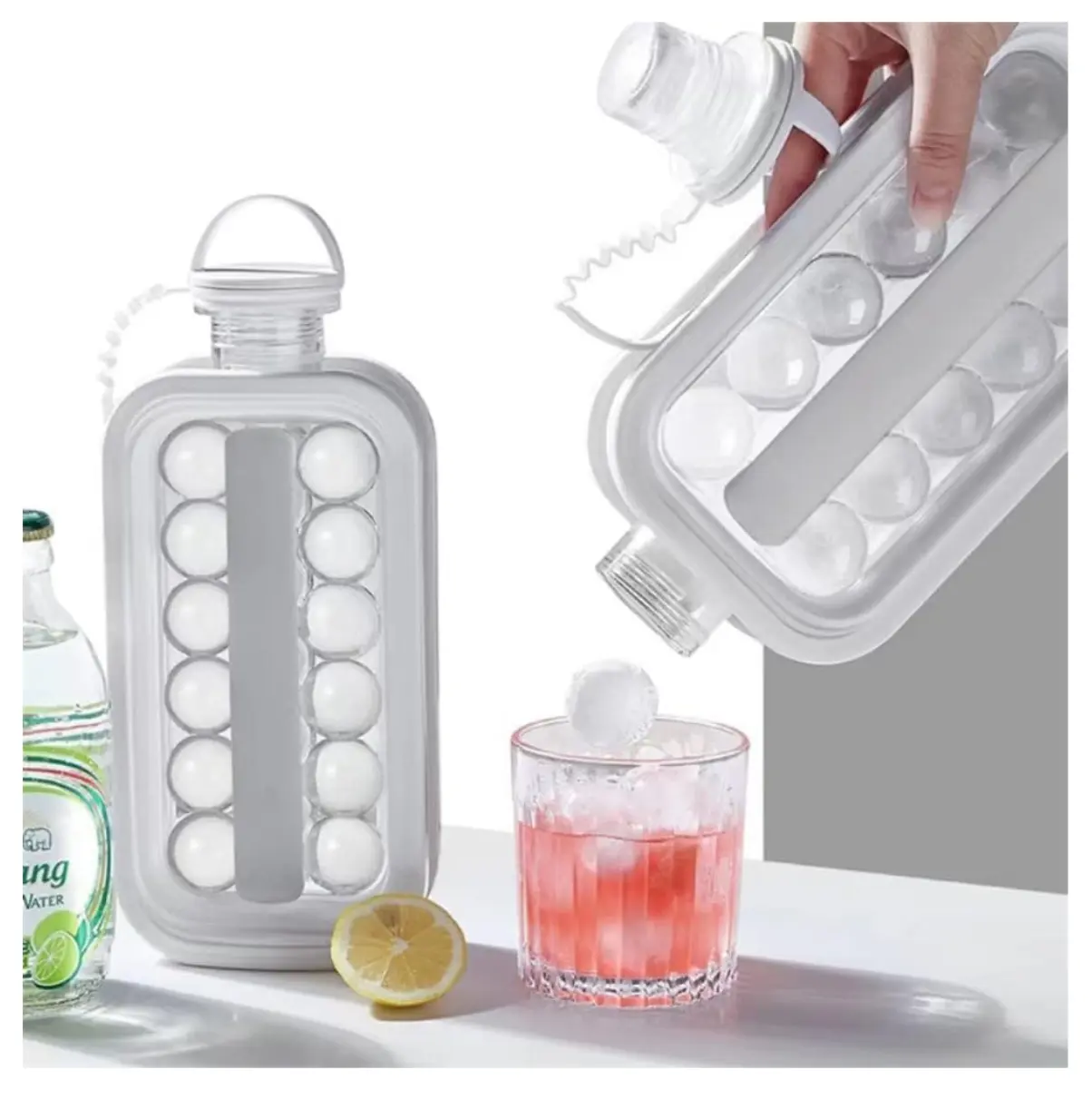Botella hielera con moldes circulares liberando hielos en vaso con bebida rosada y rodaja de limón.