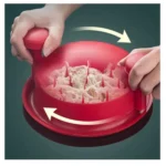 Desmechador de pollo en acción: manos girando el utensilio rojo para desmenuzar carne.