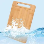Tabla de cortar de madera de bambú en agua con salpicaduras, ideal para cocina.