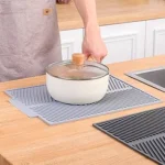 Tapete de cocina multifuncional gris con olla blanca sobre él, secando platos.