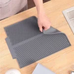 Tapete de cocina multifuncional gris sobre mesa de madera, mano colocando platos.