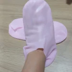 Medias spa hidratantes de silicona rosa cubriendo un pie y tobillo sobre superficie de madera.