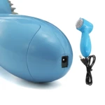 Mini masajeador eléctrico azul tipo tiburón con cargador USB y cepillo.