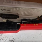 Cepillo secador alisador de cerámica rojo y negro, con botones dorados y cable.