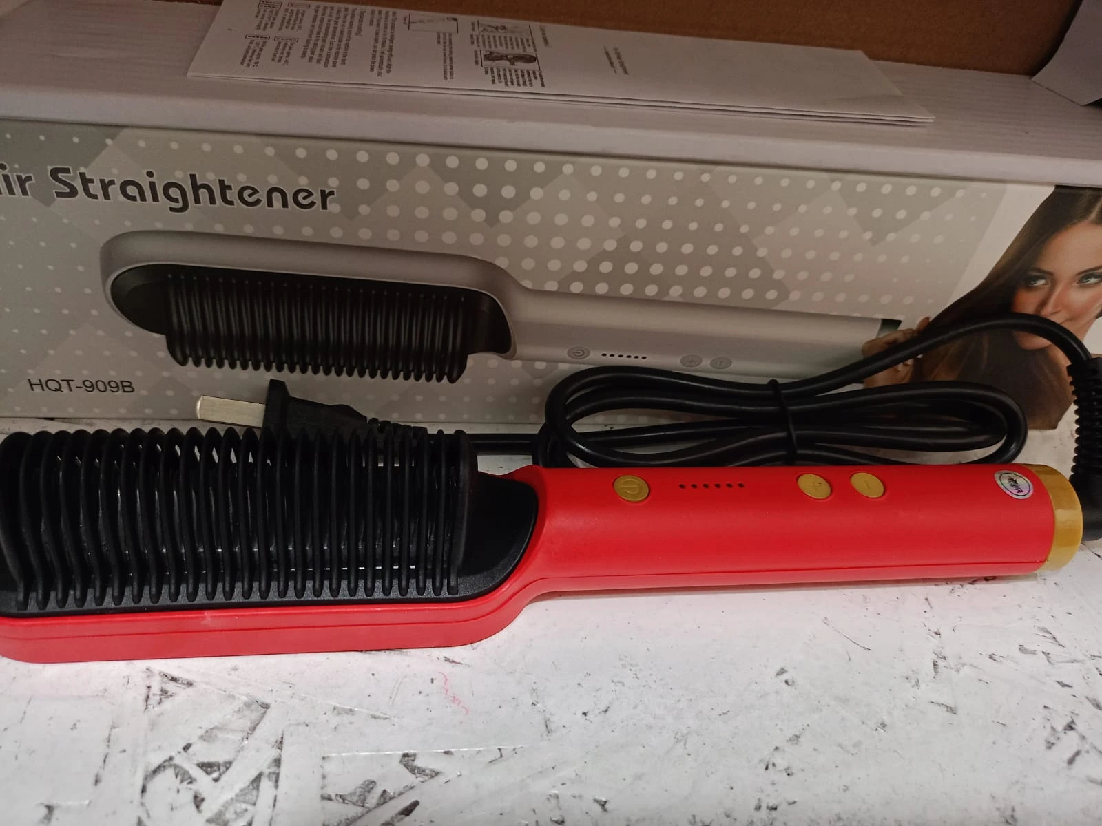 Cepillo secador alisador de cerámica rojo y negro, con botones dorados y cable.