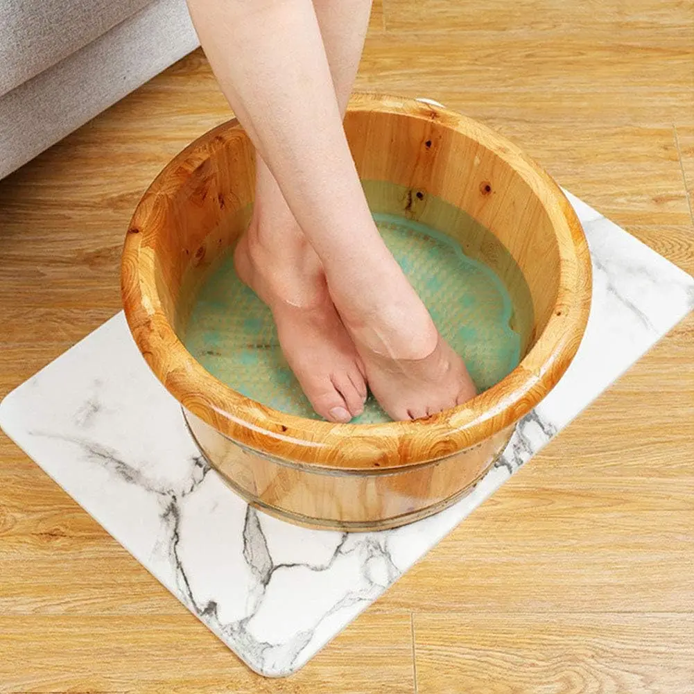 Tapete masajeador para pies en tina de madera con agua tibia, ideal para relajación y cuidado personal.