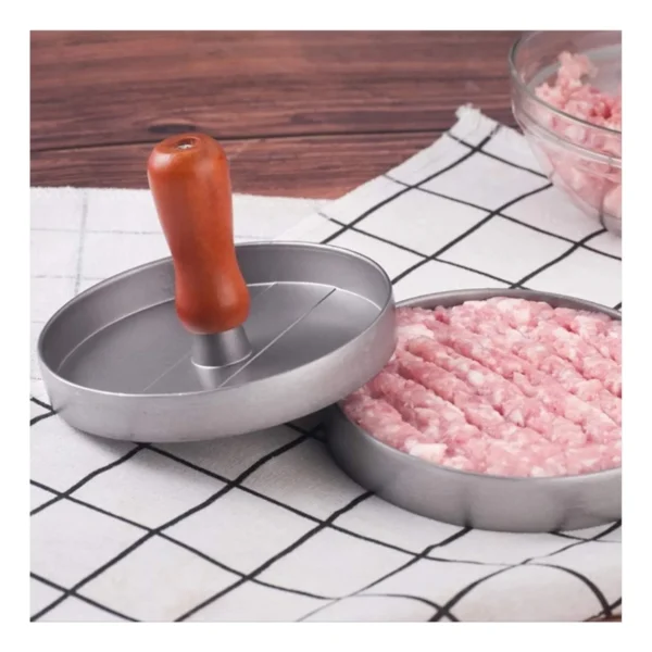 Molde para hamburguesas de carne con prensa de madera sobre fondo a cuadros.