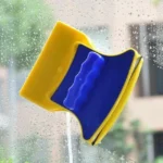 Limpiador magnético de doble cara para ventanas, amarillo y azul, limpiando vidrios mojados.