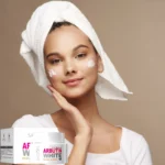 Crema facial aclarante Arbutin Sadoer con nicotinamida, aplicada por una joven con toalla en la cabeza.