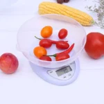 Gramera con recipiente transparente, mostrando tomates, chiles y un durazno.