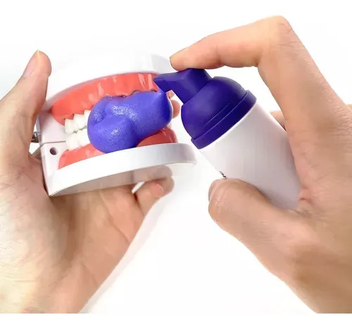 Persona aplica espuma blanqueadora Dentalx2 en modelo de dientes para demostración.