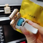 Ambientador para carro con diseño de perfume Channel, clip dorado y pastilla azul.