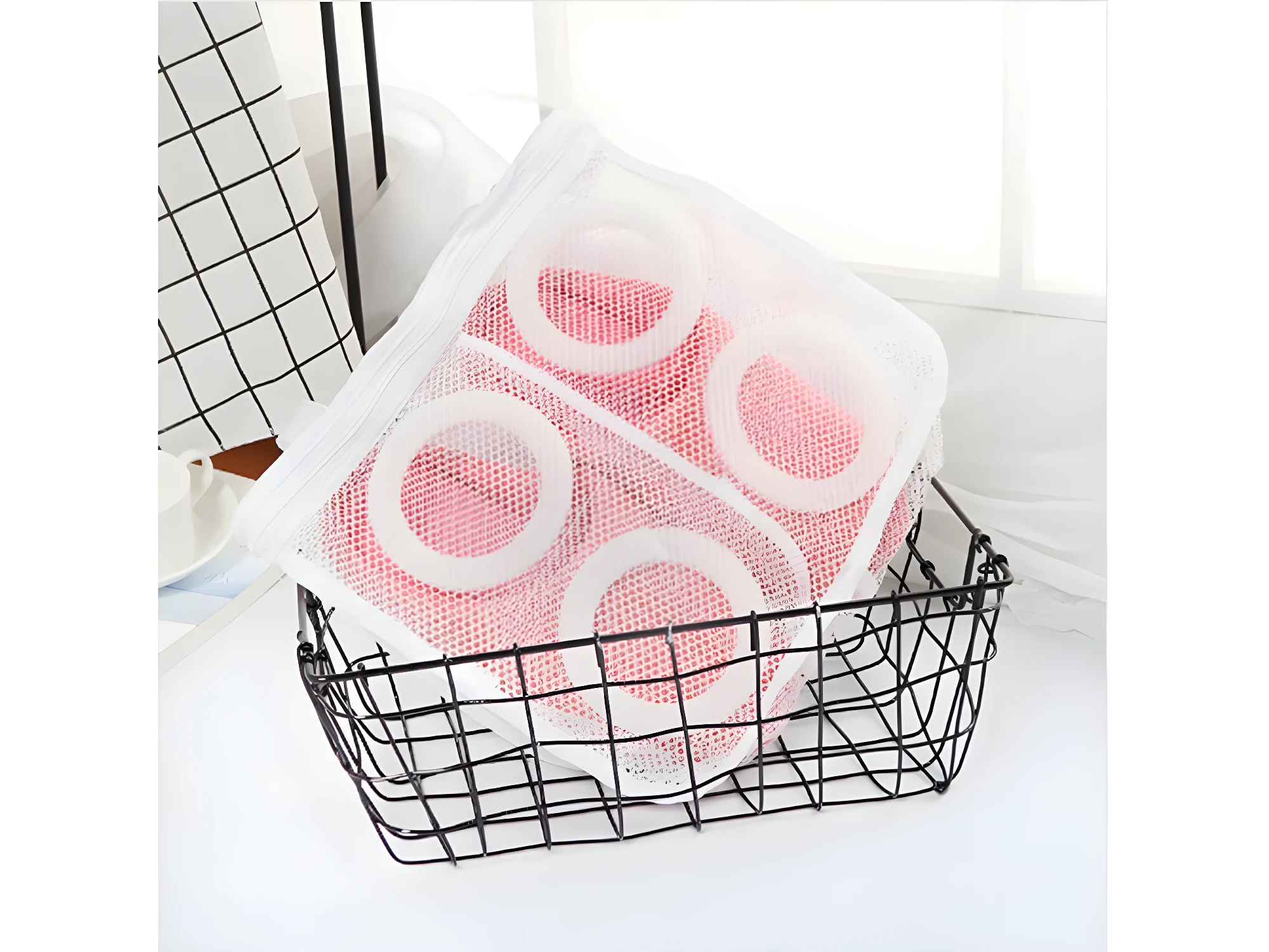 Set x2 bolsas para lavar zapatos en malla blanca con diseño de círculos rosas en interior, dentro de canasta negra.