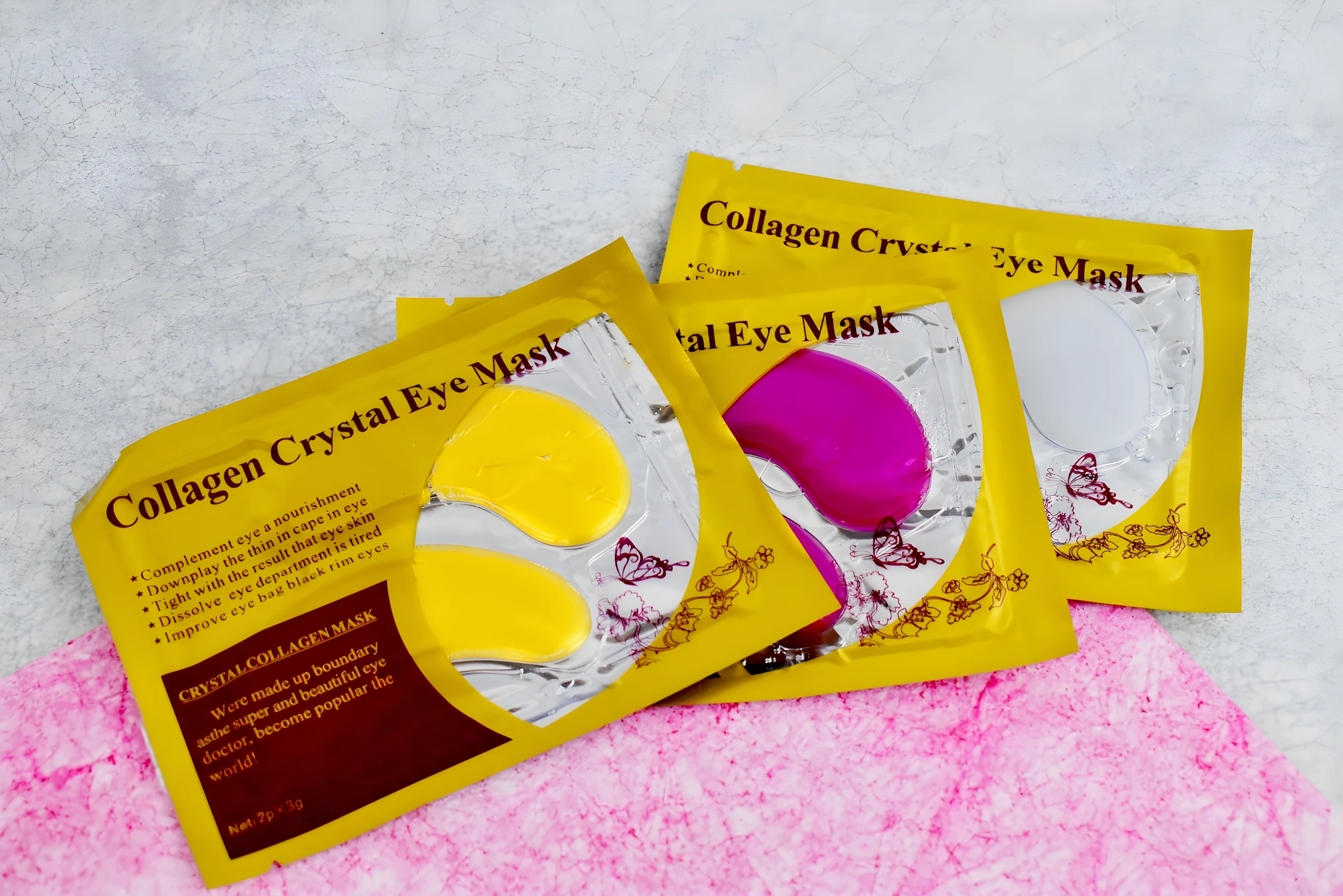 Pack de 3 mascarillas para ojeras de colágeno, con parches amarillos y rosas, sobre fondo texturizado.