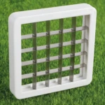 Cortador descorazonador de manzanas con cuchillas de acero inoxidable sobre césped verde.