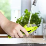 Picador triturador de ajo verde bajo el chorro de agua, fácil de limpiar.
