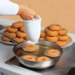 Set x2 Molde Donas: Preparando donas caseras recién fritas en sartén con molde dispensador.