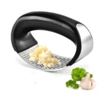 Picador de ajos ergonómico de acero inoxidable con ajo picado y perejil fresco.