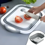 Tabla multifuncional con escurridor cortando tomates, ideal para cocina.