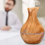 Humidificador difusor de aroma con diseño de madera y vapor saliendo, frente a un hombre desenfocado.