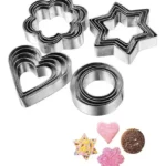 Cortadores de galleta en forma de corazón, flor y estrella, con galletas decoradas.