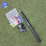 Kit de caña de pescar con carrete, anzuelos, señuelos y boyas en césped artificial.
