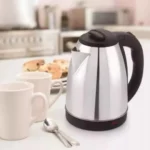 Jarra eléctrica Scarlet 2 Litros plateada con asas negras, junto a dos tazas blancas y galletas.