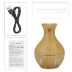Humidificador difusor de aroma con acabado en madera, incluye manual y cable USB.