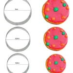 Cortadores de galleta redondos de 3 tamaños: 5, 4.2 y 3.2 cm, junto a galletas decoradas.