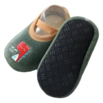 Zapatilla caminador verde con dinosaurio y suela antideslizante para bebés.