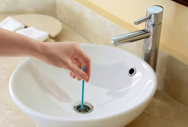 Varilla para desatascar desagüe de lavabo, utilizada por mano para limpiar.