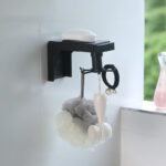 Organizador giratorio negro para baño con jabón, esponja y cepillo facial.