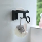 Organizador giratorio negro para baño con jabón, esponja y cepillo facial.