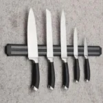 Soporte magnético negro con 6 cuchillos de cocina de varios tamaños en pared gris.